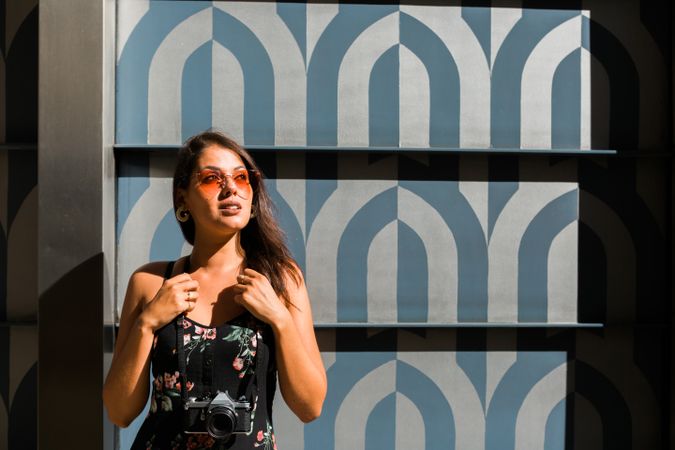 Dreamy stylish woman in sunglasses standing on city street