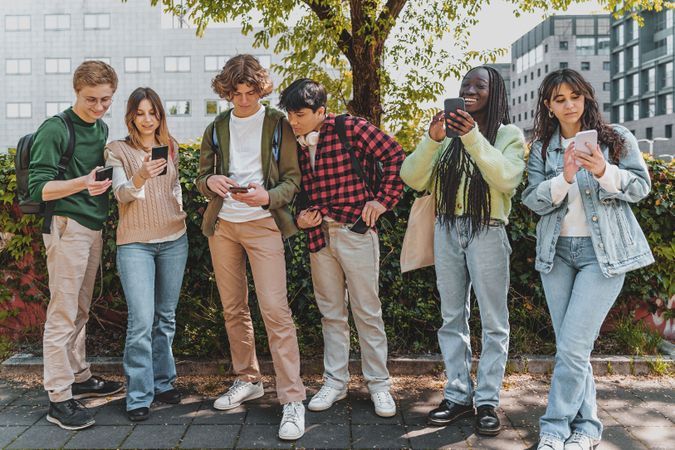 Multi-ethnic group of students checking their phones on campus