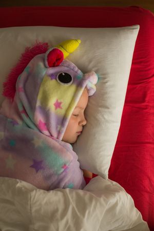 Girl in unicorn pajama sleeping in bed