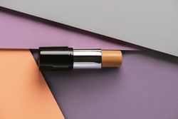 Concealer stick on modern background with geometric shapes.