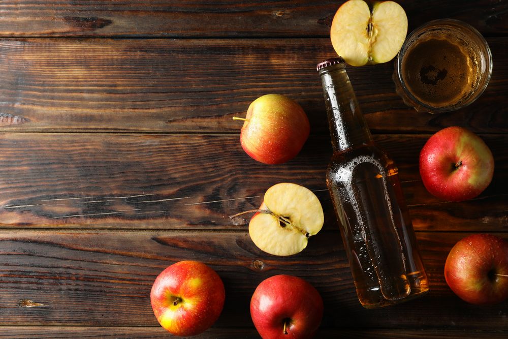 Composition with cider and apples on wooden background