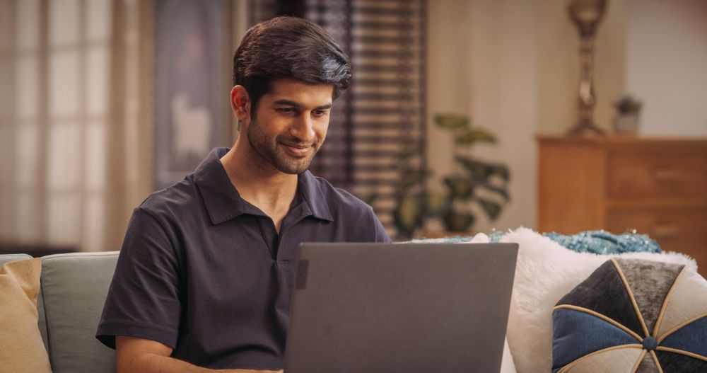 Portrait of Indian Man Working on Laptop at Home: Focused and Productive, Finishing Remote Work Projects, Managing Customer Service Feedback