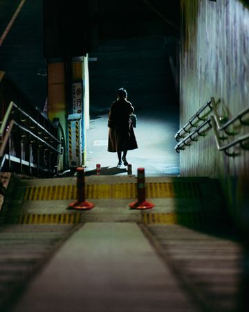 Back view of woman wearing coat down the staircase at the subway