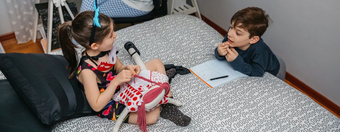 Children playing and doing homework talking with their mother who works at home