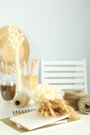 Table of arts and crafts supplies in bright home crafting room, with dried flowers and yarn