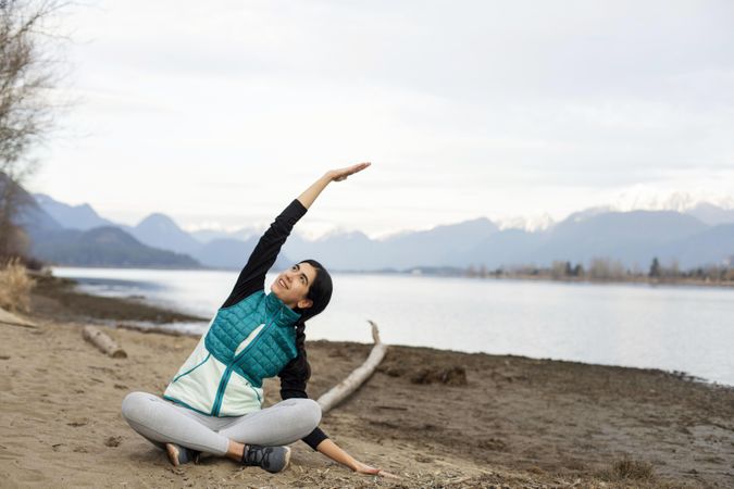 Happy young female stretching on the lake shore