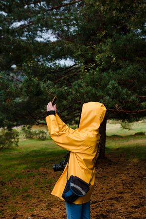 Woman in hoodie and yellow raincoat taking selfie