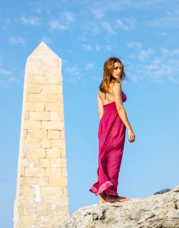 Woman in dress standing near stone monument