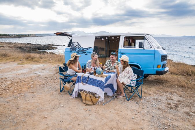 group of friends sitting in chairs next to a minivan