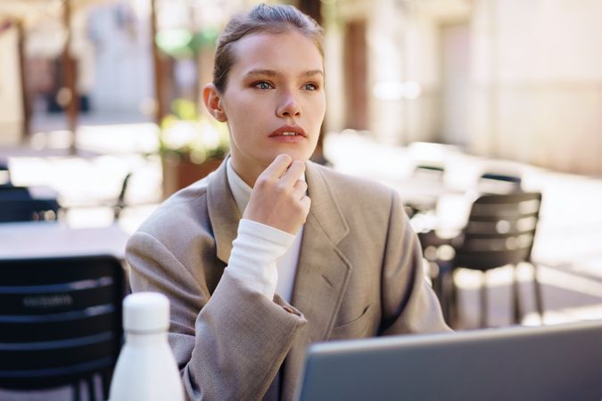 A thoughtful professional woman diligently working outdoors on her laptop, immersed in her tasks