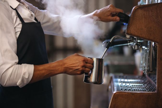 Coffee shop worker preparing coffee on steam espresso coffee machine