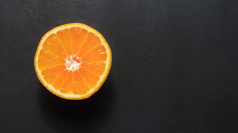 Top view of a half cut orange placed on a dark background