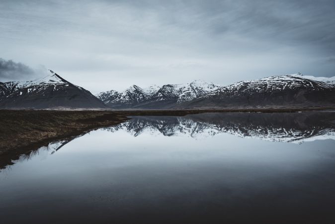 Snowcapped mountains reflected In still lake