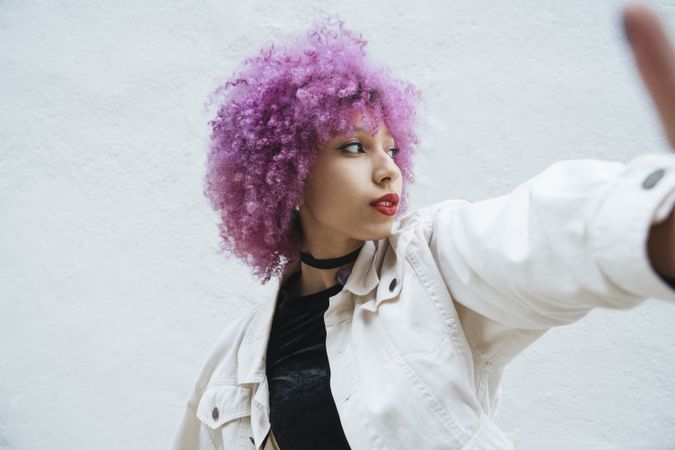 Stylish woman with pink hair trying to catch camera