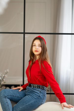 Portrait of teen girl sitting on sofa by window.
