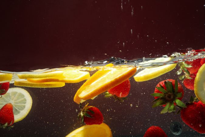 Side view of citrus slices and strawberries floating in water