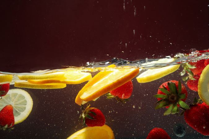 Side view of citrus slices and strawberries floating in water
