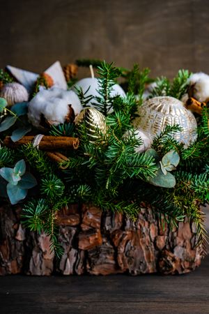 Close up of wooden Christmas center piece topped with pine and ornaments