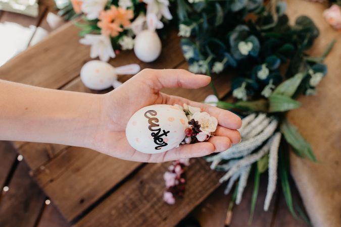young woman holding an easter egg painted by children with flowers