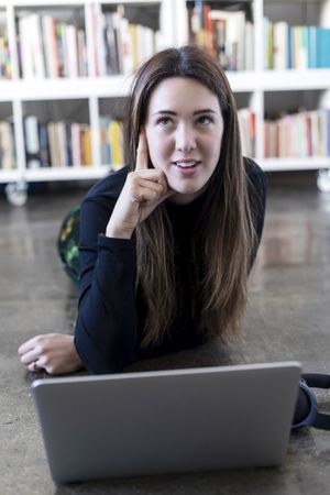 Curious entrepreneurial woman in front of laptop on floor