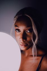 Black adult woman with illuminated balloon in darkness looking at camera