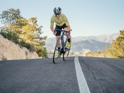 healthy man riding a bicycle on a mountain road in a sunny day
