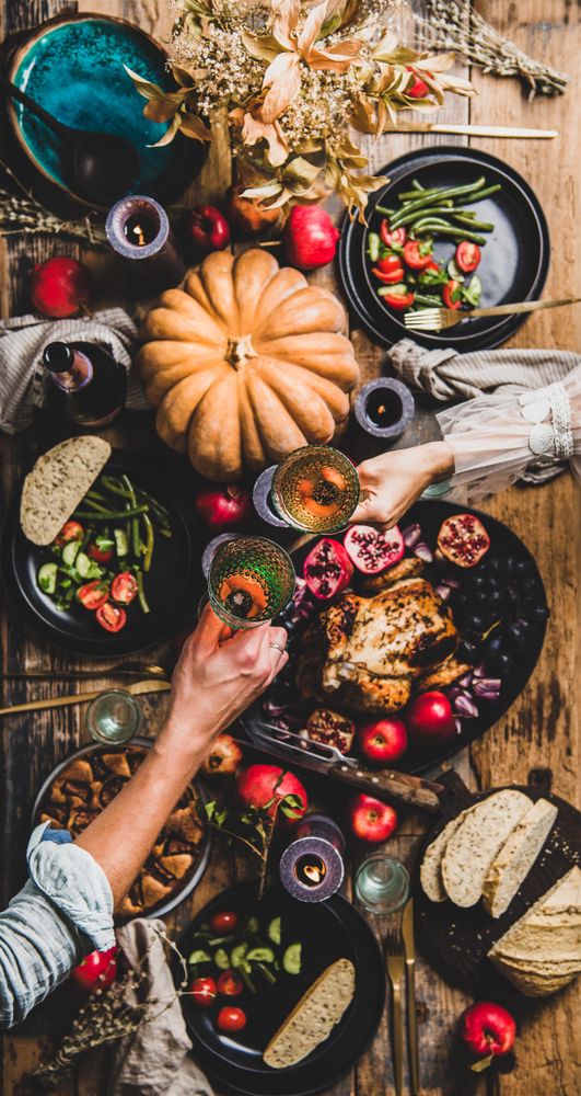 Autumnal table with squash and candles with two hands toasting with glasses of wine