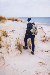 Man walking between sand field with dry grass