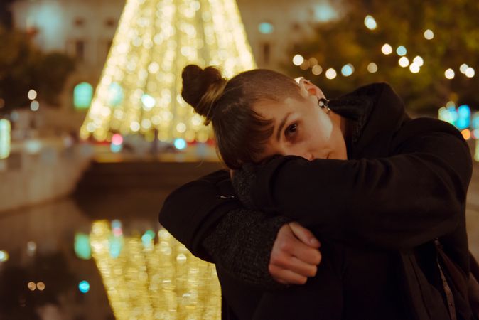 Woman in trendy outfit sitting near a Christmas tree