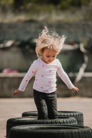 Cute girl jumping on car tires