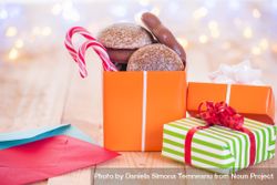 Colorful wrapped presents with cookies and candy on wood table bEOo15