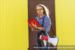 Studious woman taking notes dressed in checkered shirt against a yellow wall bYodN5