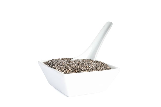 Chia seeds, ceramic plate and spoon isolated on studio background