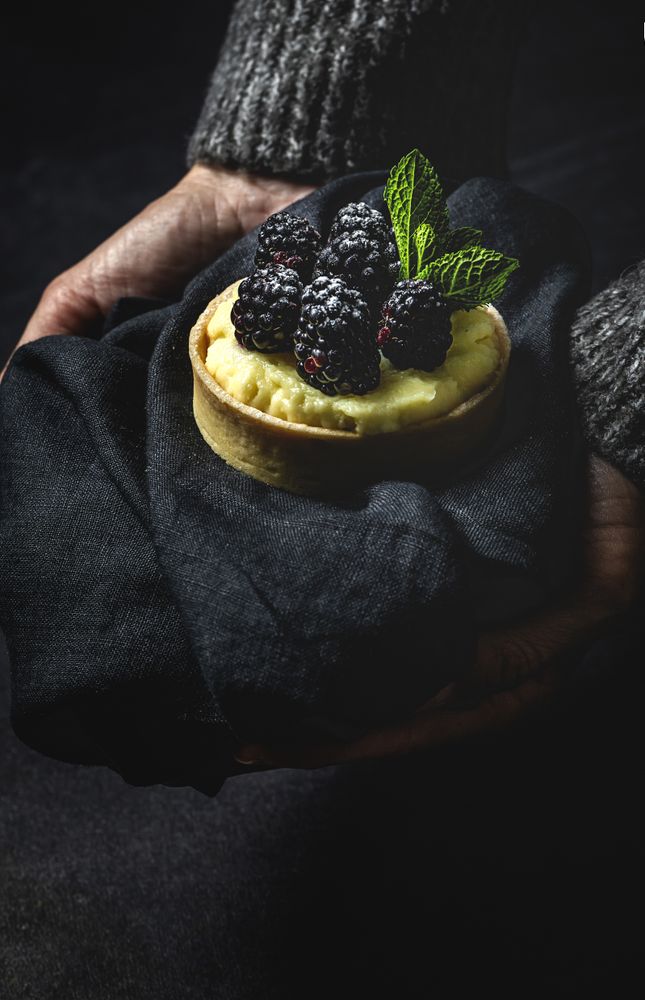 Hand holding a blackberry tartlet