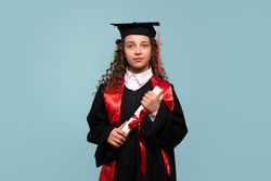 Young girl in graduation attire holding diploma with serious expression