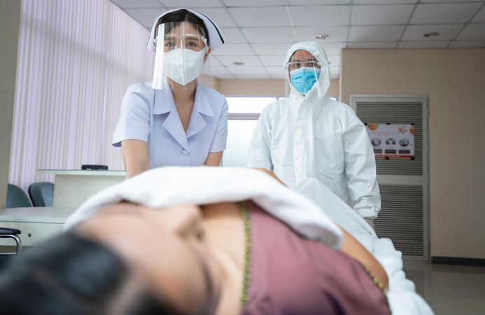 Front view of doctor and medical staff wheeling a patient to another room