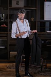Elegant man checking message on phone in wardrobe