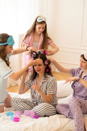 Woman in pajamas gets hair done by girls