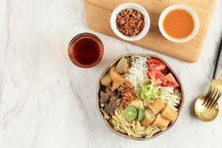 Top view of Indonesian beef noodle soup with noodles, beef, spring roll, cabbage and tomato