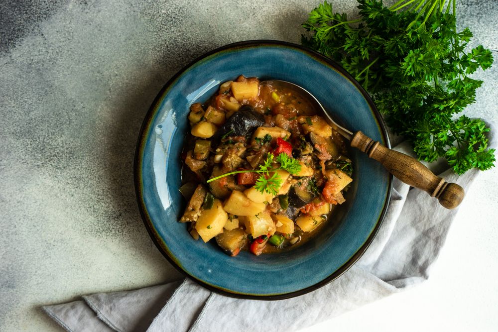 Top view of Georgian summer and autumnal dish Ajapsandali with vegetables in blue bowl with garnish