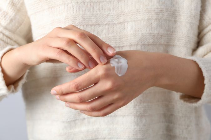 A jar of hand cream in hands on a light background.