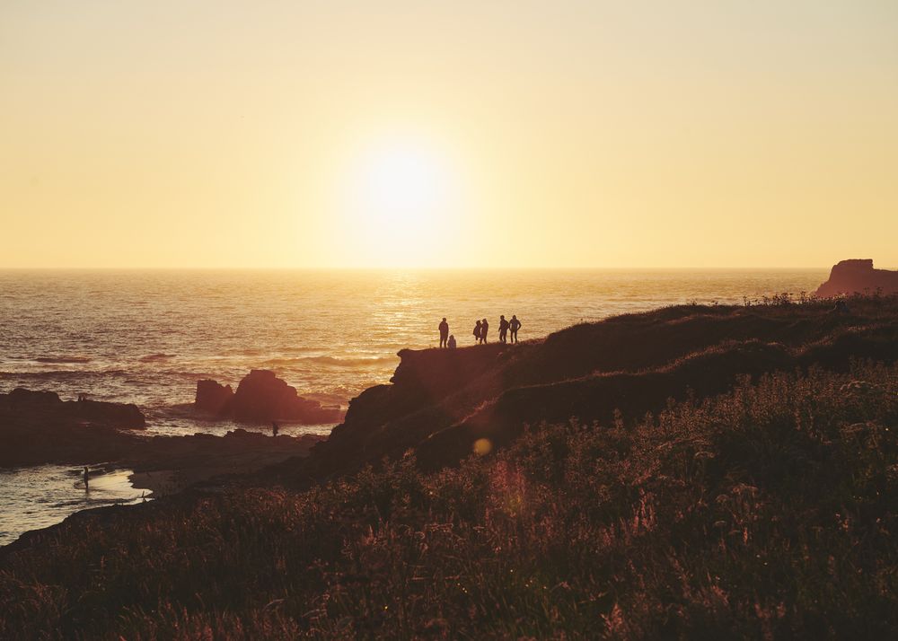 People on a cliff watching a beautiful sunset over the sea