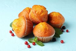 Composition with muffins and berries on blue background, close up