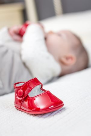 Baby red shoes and babe playing on the background