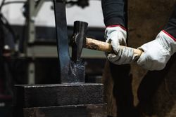 Forging hot metal with hammer in workshop