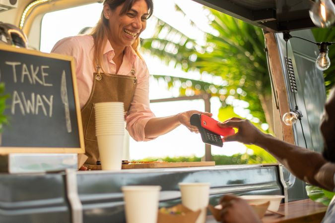 Cheerful woman paying for coffee in cafe