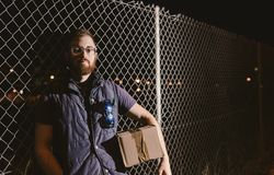 Courier with carton waiting client on street in evening