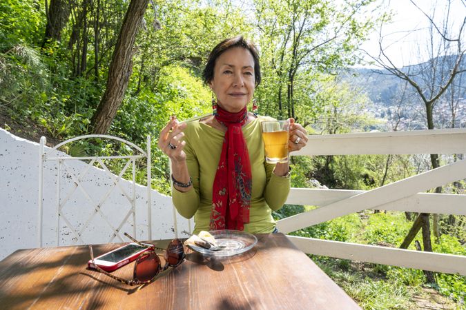 Mature woman with pipe in one hand and tea in the other