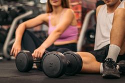 man and woman exercise workout in gym fitness breaking relax with dumbbell on the floor