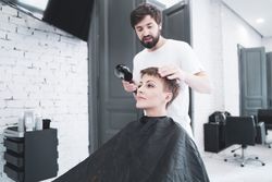 Hairdresser drying hair to woman
